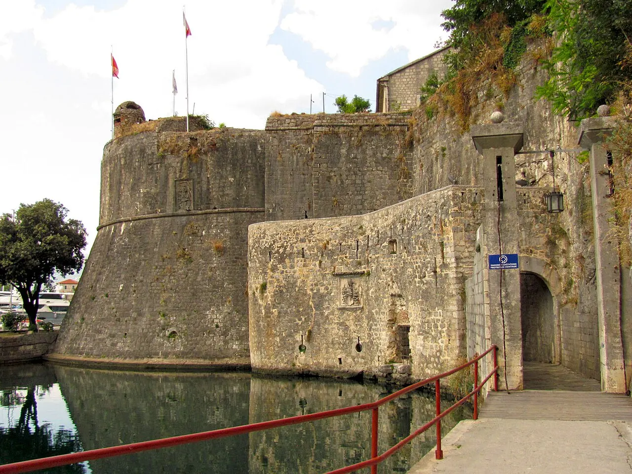 The level paved approach and ramp to the South Gate of Kotor's Old Town, stone walls and moat beside the entrance