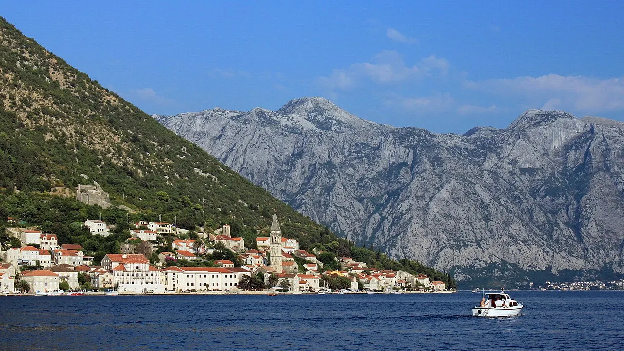 The captains' village of Perast tracing the shoreline of the Bay of Kotor, seen from the water with a small boat passing