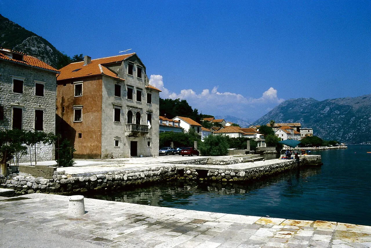 The Prcanj shore on the west side of the Bay of Kotor, small moorings and a stone church along the still water