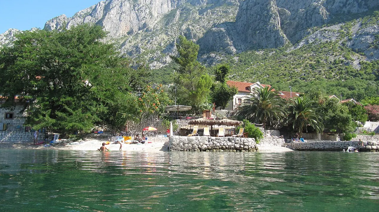 A small pebble beach at Orahovac on the quiet northern arm of the Bay of Kotor, clear water below the mountains