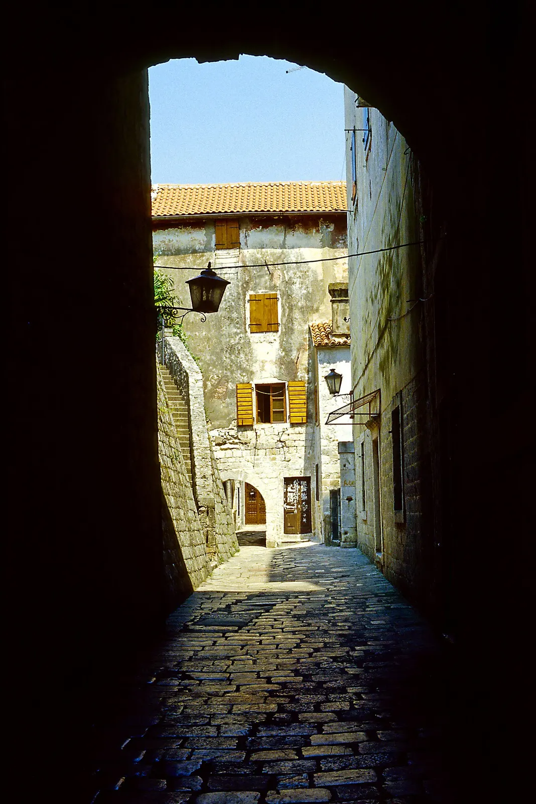 A polished limestone lane just inside Kotor's Old Town gate, seen through a stone archway
