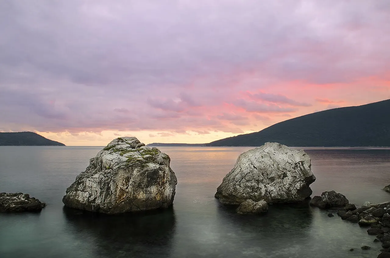 Rocks at the mouth of the Bay of Kotor at sunset, mountains rising sheer from the sea
