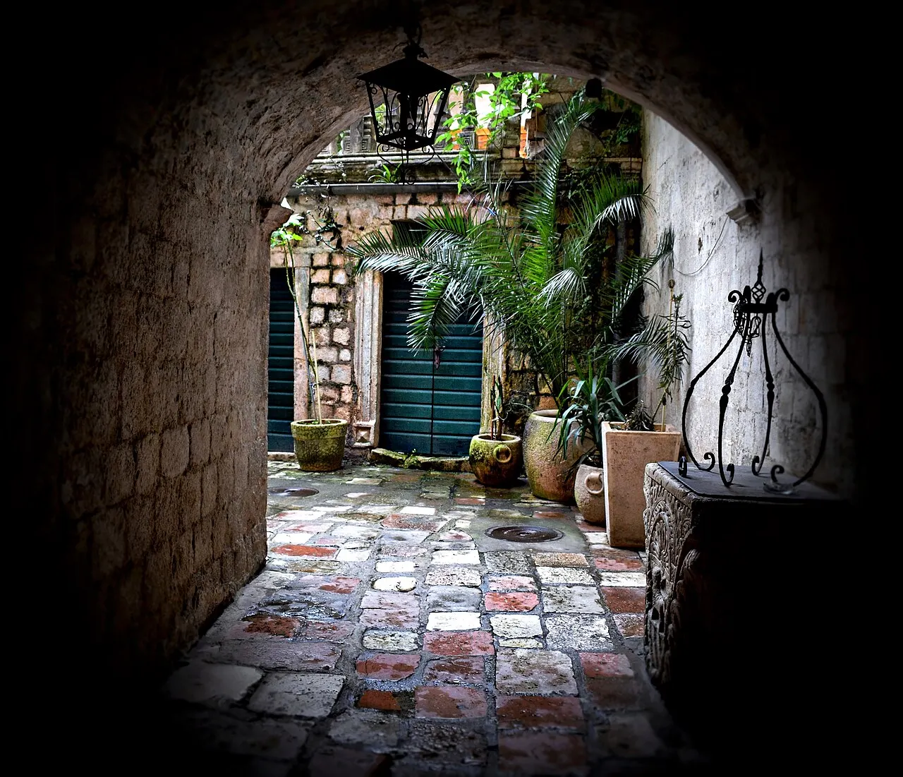 A hushed stone courtyard in Kotor's Old Town seen through an arched passage, no crowds
