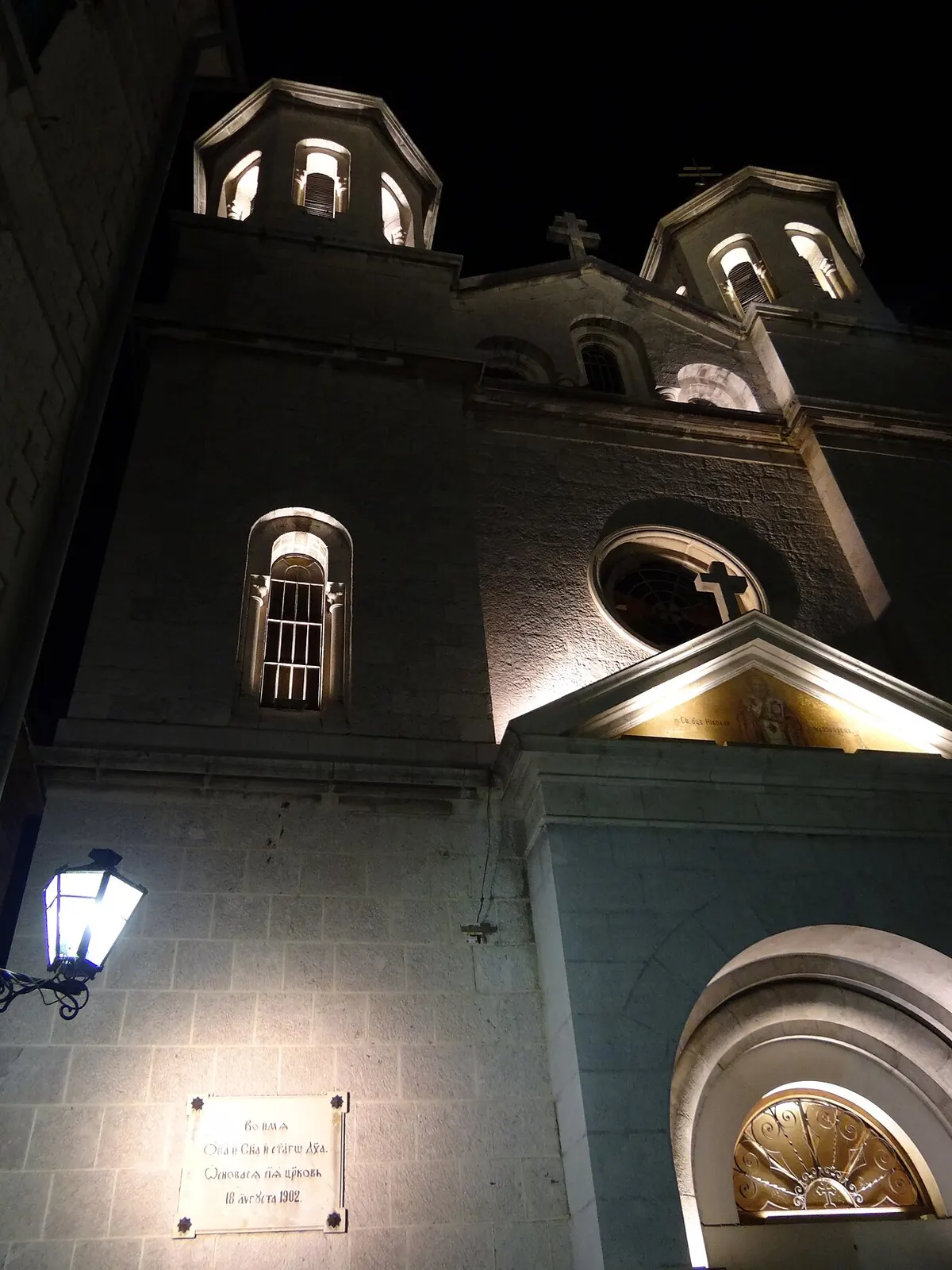 A lamplit lane and St Nicholas church in Kotor's Old Town at night, the bay still after dark
