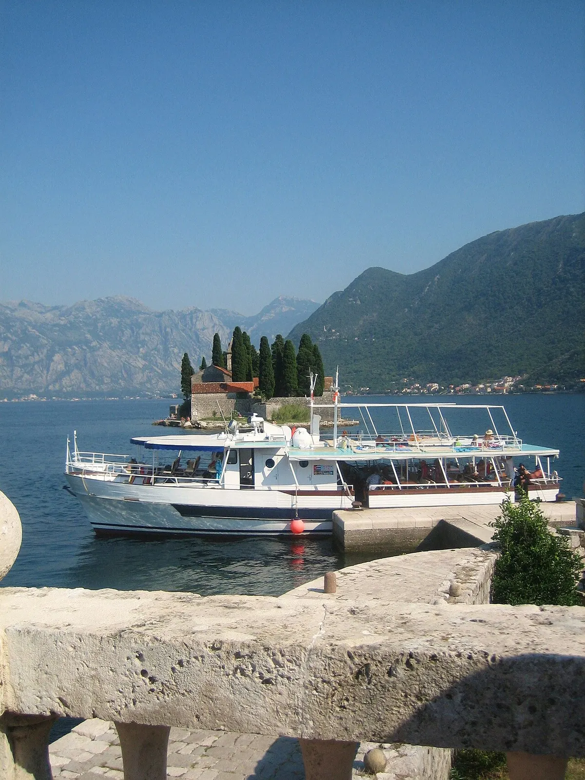 A small boat passing the island of Sveti Dorde on the glassy inner Bay of Kotor near Perast