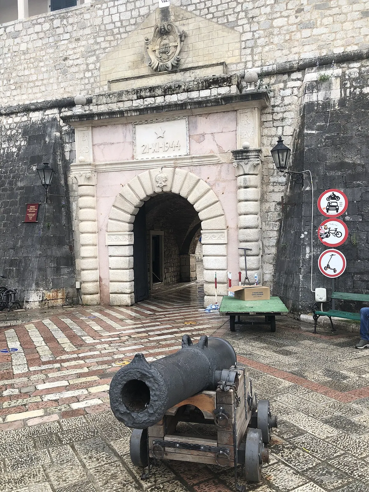 The stone main gate of Kotor Old Town with an old cannon on the cobbles in front