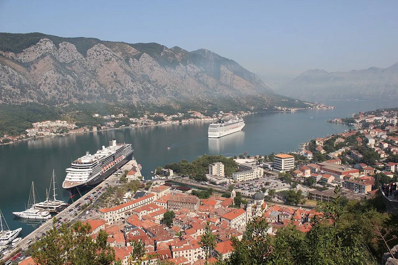 Kotor's walled old town, harbour and ships in the Bay of Kotor with mountains rising behind