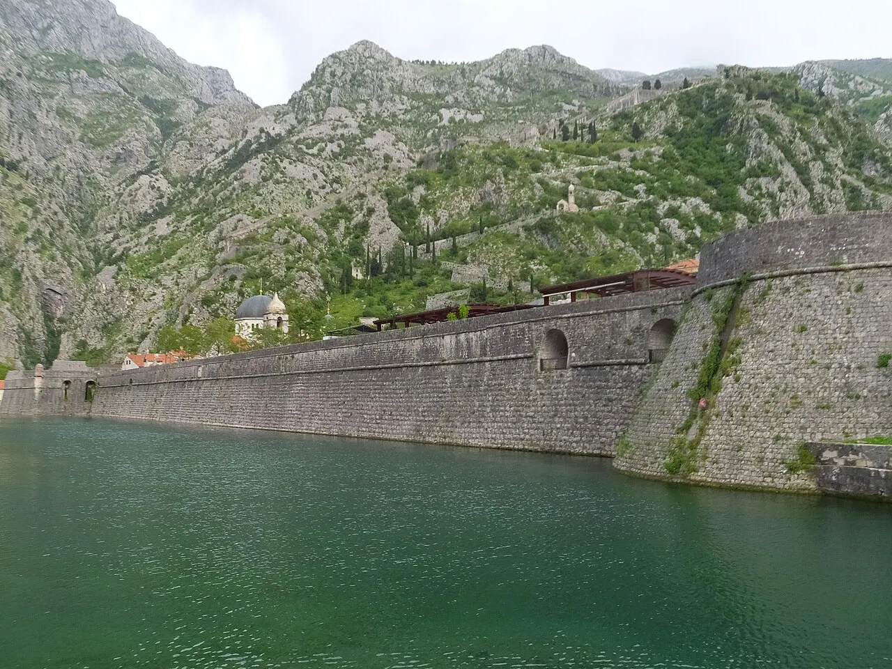 Kotor's city walls beside the moat with the ramparts climbing the cliff to the fortress behind