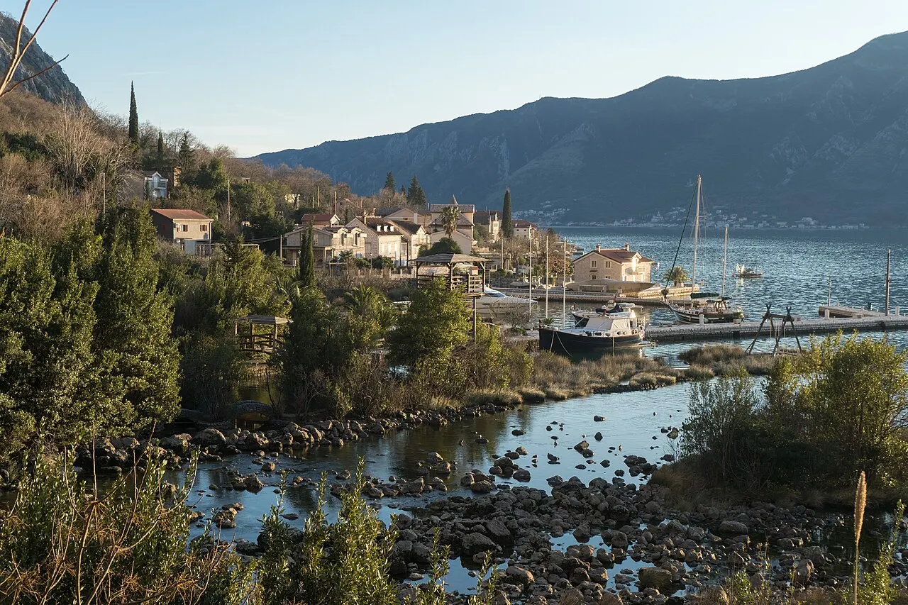 Ljuta village where the short river meets the Bay of Kotor, stone houses, boats and mountains across the water