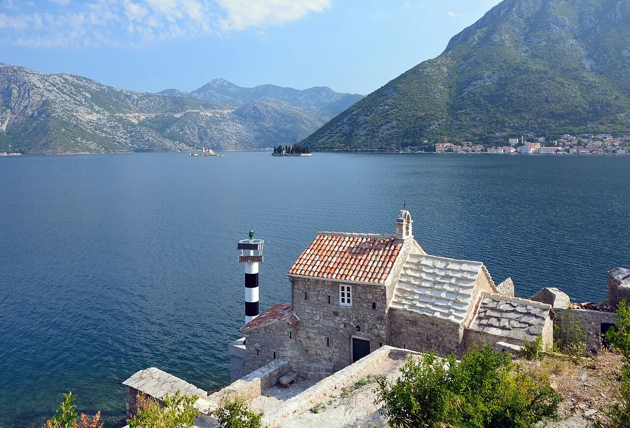 The bay road threading the shore of the Bay of Kotor below the mountains, Perast beyond