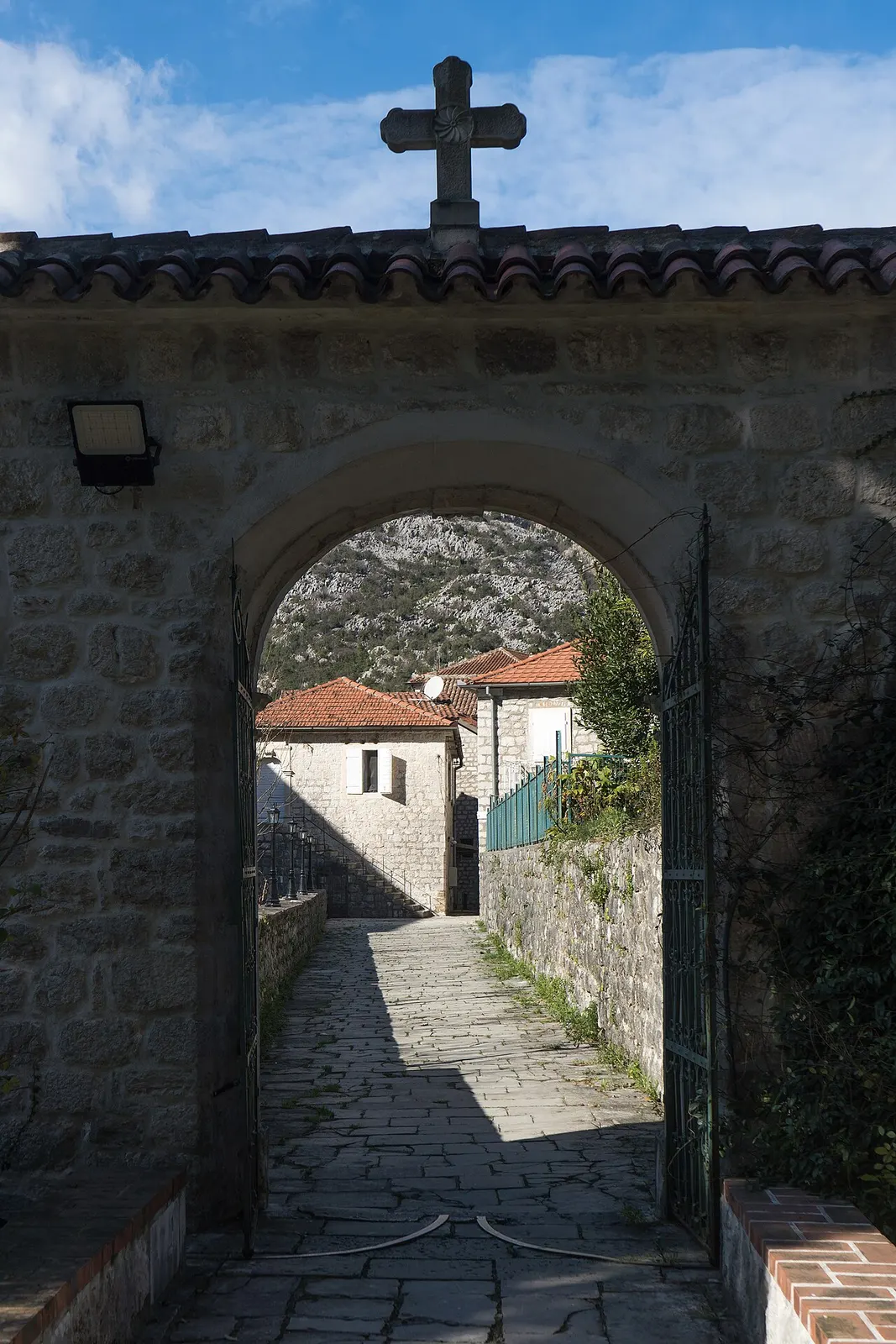 A quiet bayfront street in Risan with ordinary stone houses beside the calm bay